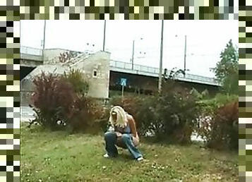 Blonde girl takes a piss right on the ground