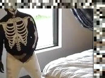 skeleton mask in pantyhose and jeans at hotel window