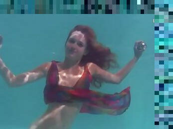 Young redhead swims in a pretty dress