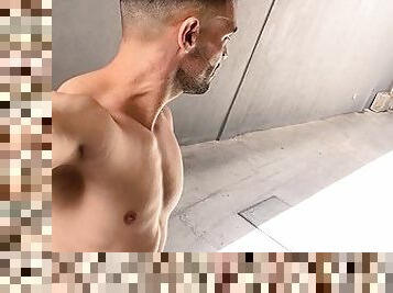 Handsome man walks naked on public parking garage and next to crowded street