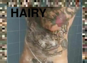 Tattooed and hairy hunk scrubs down in the shower