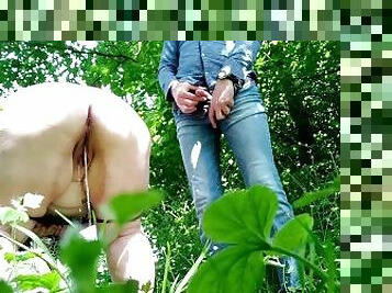 Mother-in-law bends down deeply to pee in nature next to son-in-law