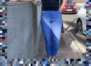 Girl peeing in jeans and walking on the public street