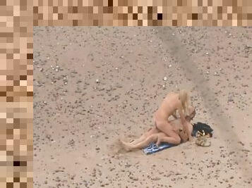 Babe with tan lines sits on a dick on the beach