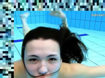 Beautiful girl swims and smiles underwater